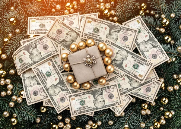 Winter background of fir branches. Adorned with gold baubles. Christmas card. Top view. Xmas congratulations. A lot of money and a gift in the middle. Light effect.