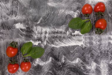 Buğday unu ile siyah arka plan üzerine yayıldı. Domates fesleğen yaprakları ile
