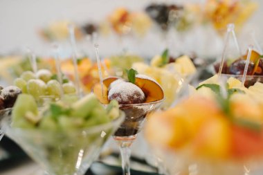 Erikli, üzümlü, kivili ve diğer meyveli bardaklar. Tatlılar, meyve salataları şenlik masasında.