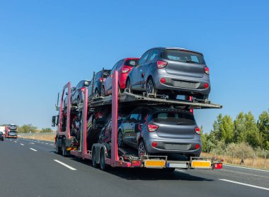 Büyük araba taşıyıcı römork ranza platformda arabalarla. Araba taşıma kamyonu karayolu üzerinde