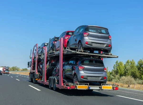 Büyük araba taşıyıcı römork ranza platformda arabalarla. Araba taşıma kamyonu karayolu üzerinde