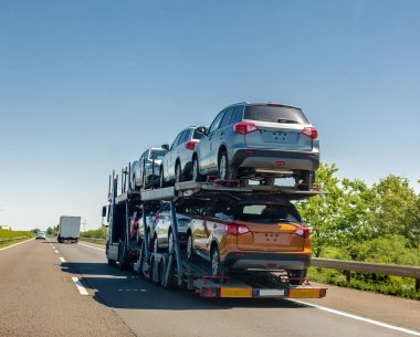 Araba taşıyıcı römork ile ranza platformda yeni arabalar. Araba taşıma kamyonu karayolu üzerinde