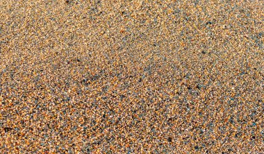 Güneşli sahil kumu. Çok renkli kaba kum arka plan. Seçici odak