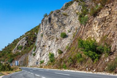 Dağ yolundan Makedonya. Yüksek rock çelik net tarafından korunmaktadır. Renkli Hills ormanıyla kaplı manzara.