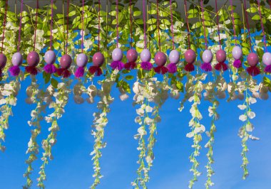 Renkli Paskalya yumurtaları ve çiçek dekor mavi gökyüzü arka plan üzerinde asılı. Otantik bir canlı çiçek dekorasyon