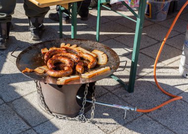 Kızartma sosis ve lezzetli bir açık barbekü propan disk Ocak üzerinde domuz yağı parçaları. Sosis geleneksel olarak, tüm gastronomi festivaller hazırlanır.