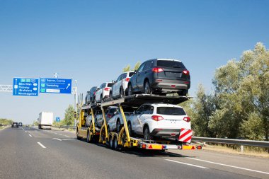 Büyük araba taşıyıcı römork ile ranza platform üzerinde Satılık yeni arabalar. Araba taşıma kamyonu karayolu üzerinde
