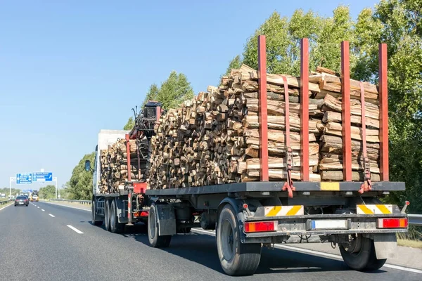 Large truck with timber on the highway. Trailer with firewood