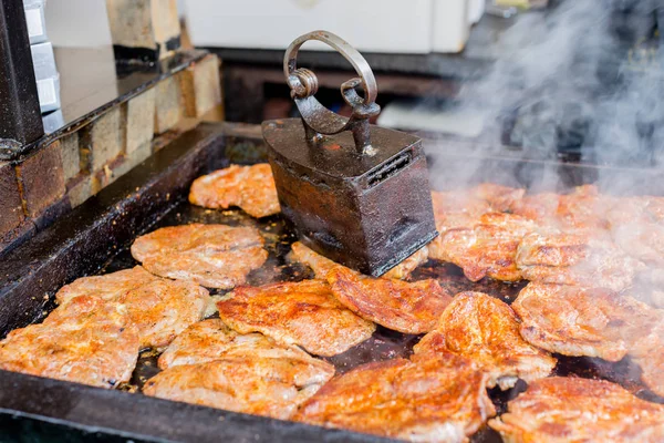 Bifes de carne suculentos grelhados em churrasco sob prensa de grade de ferro vintage no festival de comida de rua — Fotografia de Stock