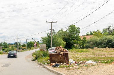 Yol yakınında inşaat atıkları için paslı metal konteyner taşıyordu. Konteynır etrafında yerde çöp