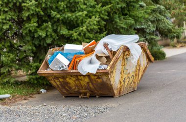 Karton kutular ve plastik çöp ile inşaat atık için paslı metal konteyner aşırı akan
