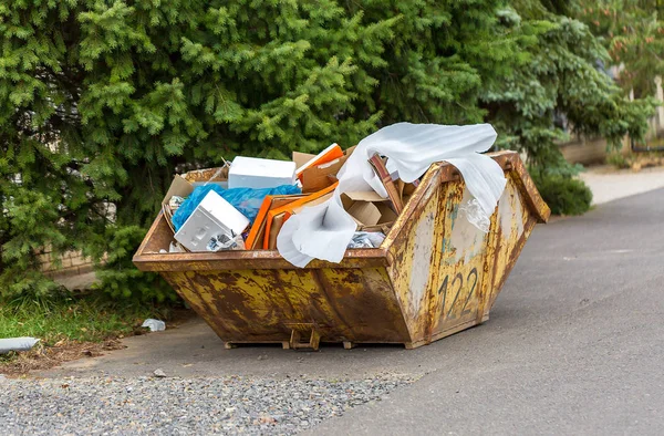 Karton kutular ve plastik çöp ile inşaat atık için paslı metal konteyner aşırı akan