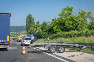 Tatabanya, Macaristan. 25 Haziran 2019, otoyolda araba kazası. Çarpışmadan sonra devrilen araba, ambulans, polis arabası ve yerleştirilmiş platform römorku. Kaza mahallinde polis var.
