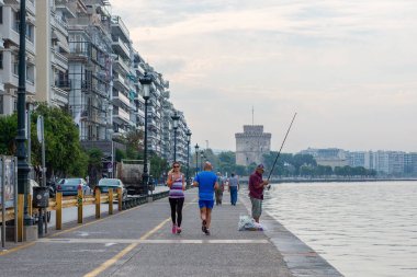 Selanik, Yunanistan - 12 Eylül 2016: Selanik deniz kenarı gezisi, Orta Makedonya, Yunanistan. İnsanlar deniz kenarında yürüyor, koşuyor, balık tutuyor. Beyaz Kule ile Skyline
