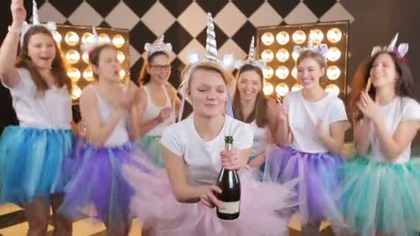 Happy young bride on girl s night out party popping champagne, laughing, have fun in colorful air tutu skirt on warm border light background — 비디오