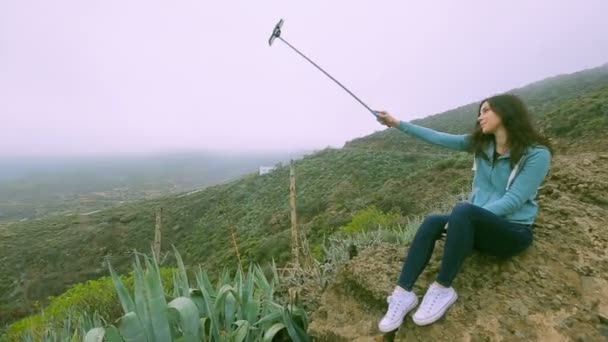 火山岩を眺めながら写真を撮る若い旅行者の女の子 — ストック動画