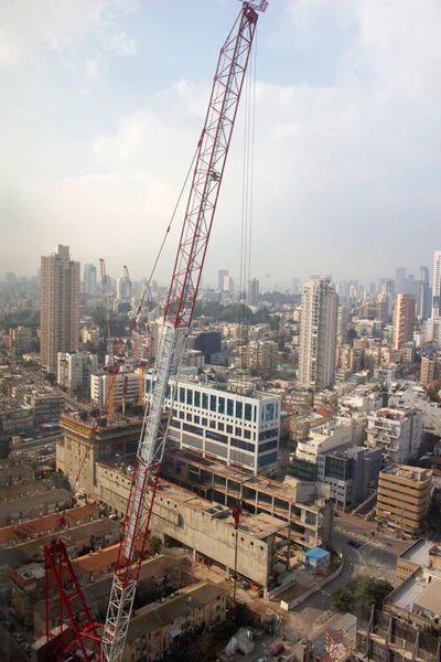Modern city. Office building top view. Crane and building construction site against blue sky. Isreal, Ramat-gan.