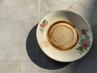 Kirli çay fincanı. Çiçek süslemesi ve desenli bir yüzeyde gölgesi var..