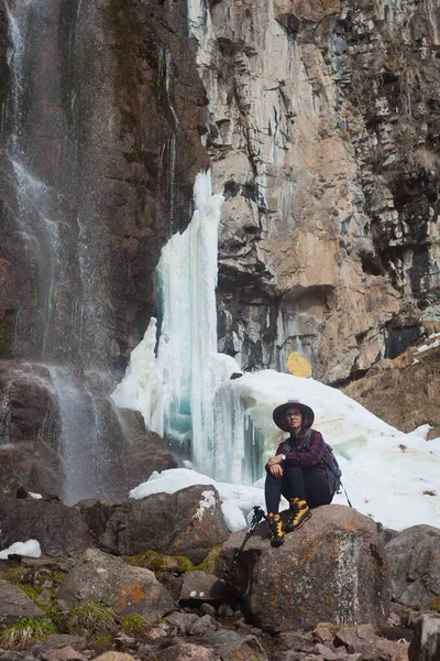 Girl in hat on the frozen waterfall and river