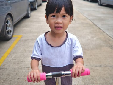 Scooter kask olmadan kamu yolda oynayan küçük Asya çocuk.