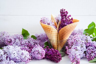 Dondurma koni natürmort hafif ahşap arka plan üzerinde lila mor çiçekler