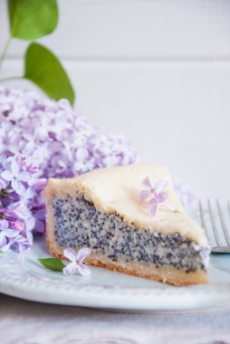 Beyaz ahşap zemin üzerine eflatun çiçekli haşhaş tohum pasta dilimi