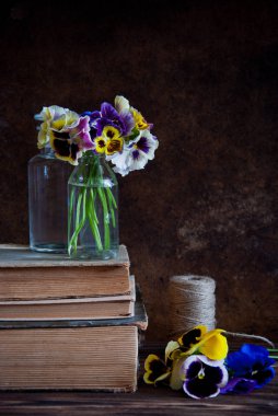 Cam şişeler, sicim ve eski kitaplar ahşap arka plan üzerinde bir top hercai menekşe