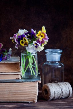 Cam şişeler, sicim ve eski kitaplar ahşap arka plan üzerinde bir top hercai menekşe