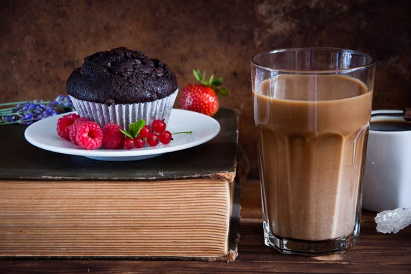 Шоколадный кекс с красными ягодами, кофе и старыми книгами — стоковое фото