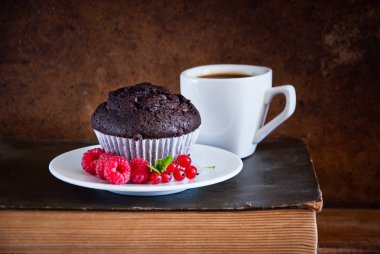 Kırmızı çilek ve siyah kahve ve eski kitaplar fincan ile Çikolatalı muffin 
