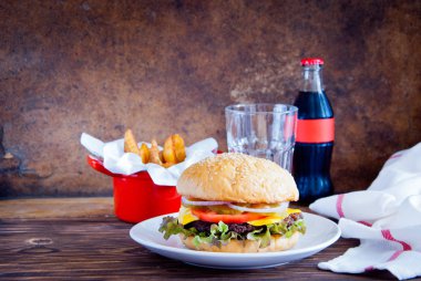 Ahşap arka planda ev yapımı burger, patates kızartması ve soğuk içecek