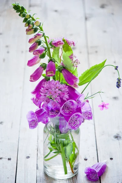 Lila virágok egy üveg váza szürke fa háttér — Stock Fotó