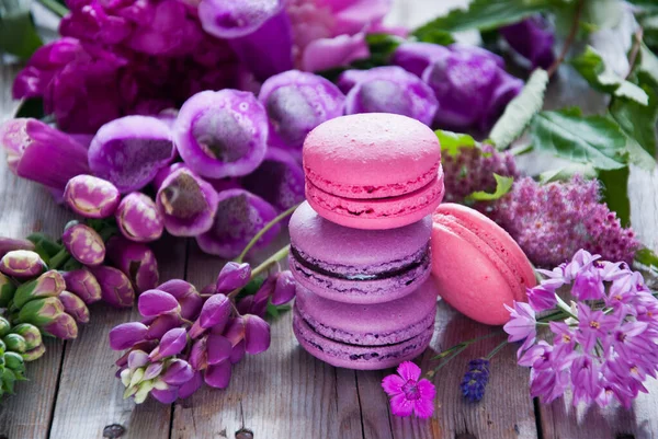 Flores roxas e rosa e macaroon em um fundo de madeira — Fotografia de Stock