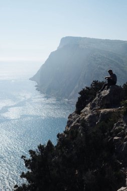 Pelerin ve denizin üzerinde oturan adam