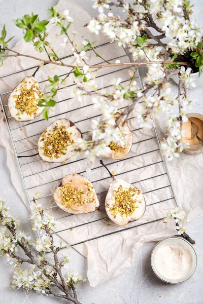 Mascarpone ve antep fıstığı ve çiçek açan elma dalları ile pişmiş armut
