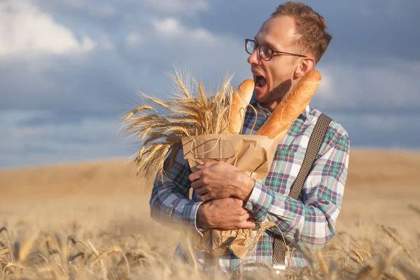 Hungry man bites baguettes in rye field