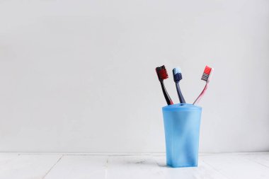 Beyaz ahşap rafta mavi fincan aile diş fırçaları