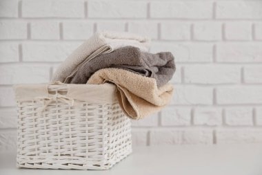 Hasır sepetin içindeki çok renkli temiz havlular beyaz masanın üzerinde beyaz tuğladan duvarlı arka plan üzerinde