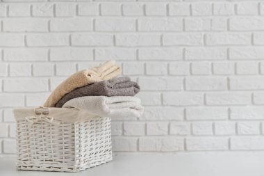 Hasır sepetin içindeki çok renkli temiz havlular beyaz masanın üzerinde beyaz tuğladan duvarlı arka plan üzerinde