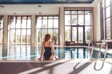 İyi tatiller. Yüzme havuzunda kokteyl içen zayıf bir genç kadın..