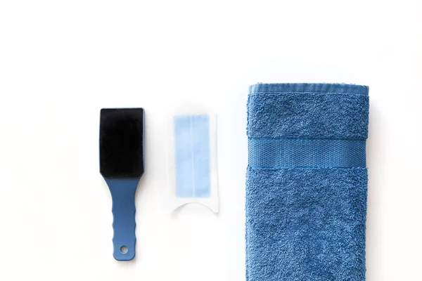 Heel scraper, disposable wax strip for depilation and blue cotton towel isolated on white. Top view. — Stock Photo, Image