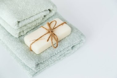 Banyo havlularına bağlanmış, beyaz zemin üzerinde kopya alanı olan katı sabun..