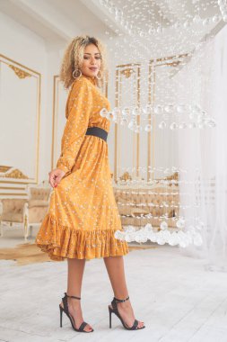 Güzel Afrikalı, şık elbiseli ve topuklu ayakkabılı bir kadın. İç kısımda kristal avizenin yanında poz veriyor..