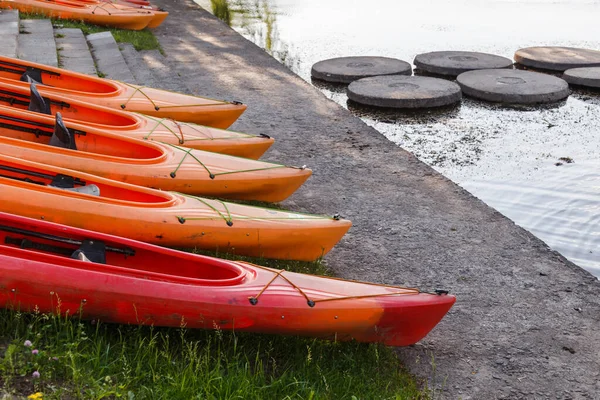 Polymer kayaks, water sports. Canoe summer club equipment. Active rest, sport, kayak. Boat for rafting on water. A few kayaks stand on rent point