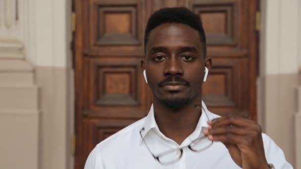 Portrait of a handsome middle aged black african male puts on his eye glasses. Concept of a good vision, freedom lifestyle, achievement and confidence — Stock Video