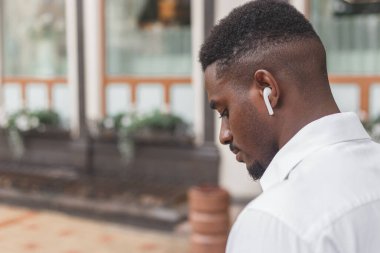 Kulaklıkla müzik dinleyen profilli bir adamın yakın plan görüntüsü.