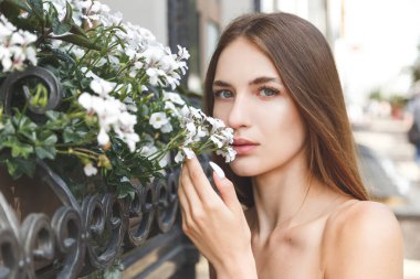 Çiçekli çalılıklarda, beyaz petunya çiçekleriyle güzel bir genç kadının şehvetli sakin portresi.
