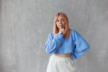 Güzel bir kadın sessizlik ya da gizlilik isterken işaret parmağını dudaklarına dayayıp 