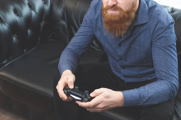 Homem com uma barba com fones de ouvido em sua mão joystick em um fundo leve — Fotografia de Stock