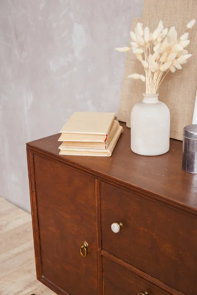 Retro skříňka s knihami a vázou v interiéru domácí kanceláře na stole. Skutečná fotka — Stock fotografie
